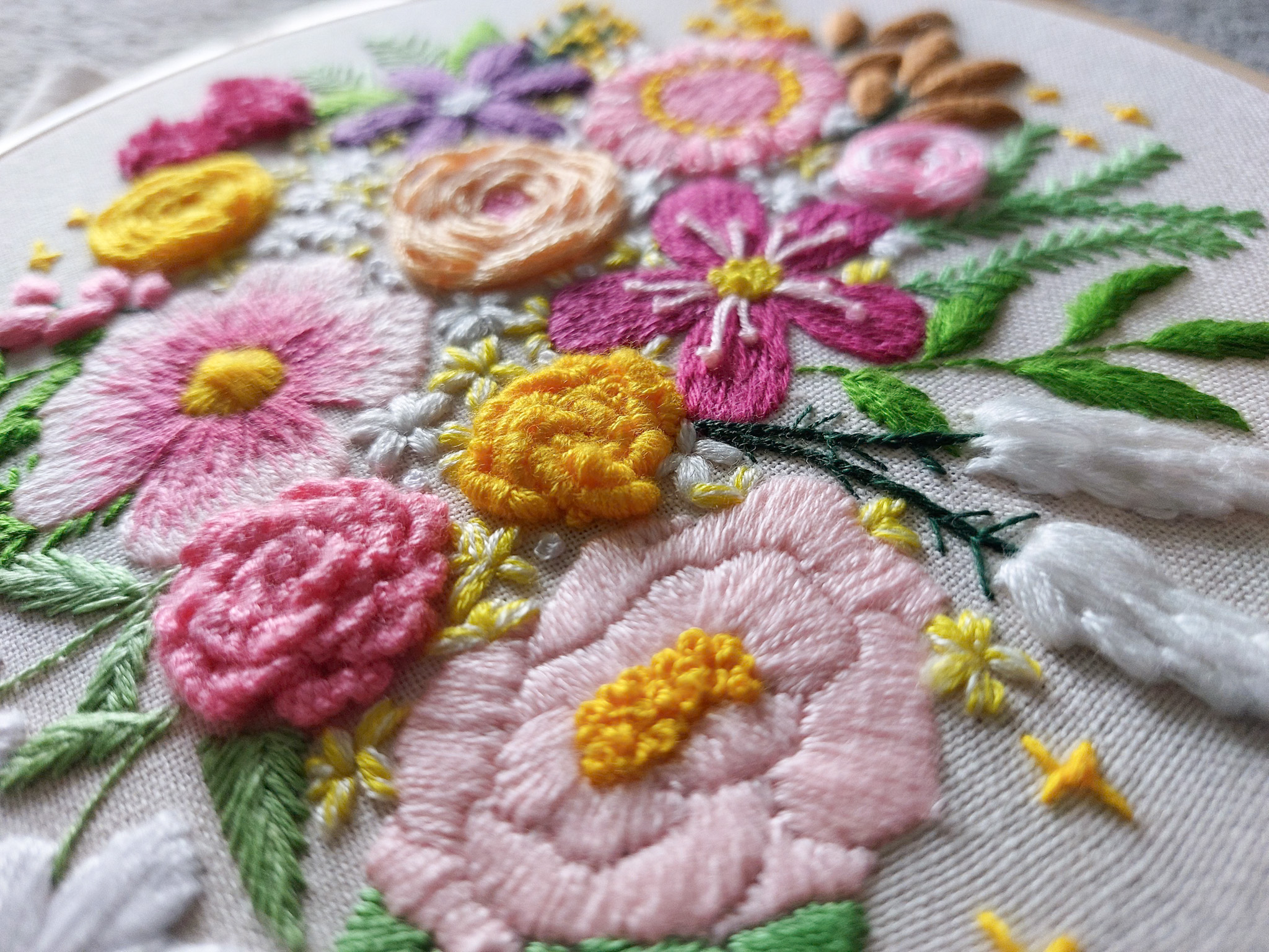 A close up of bright colourful floral embroidery stitches, showcasing a mix of advanced embroidery stitches like cast on stitch and bullion knot. This is the 'Blooming Florals' pattern from embroidery membership Bloom Embroidery Academy.