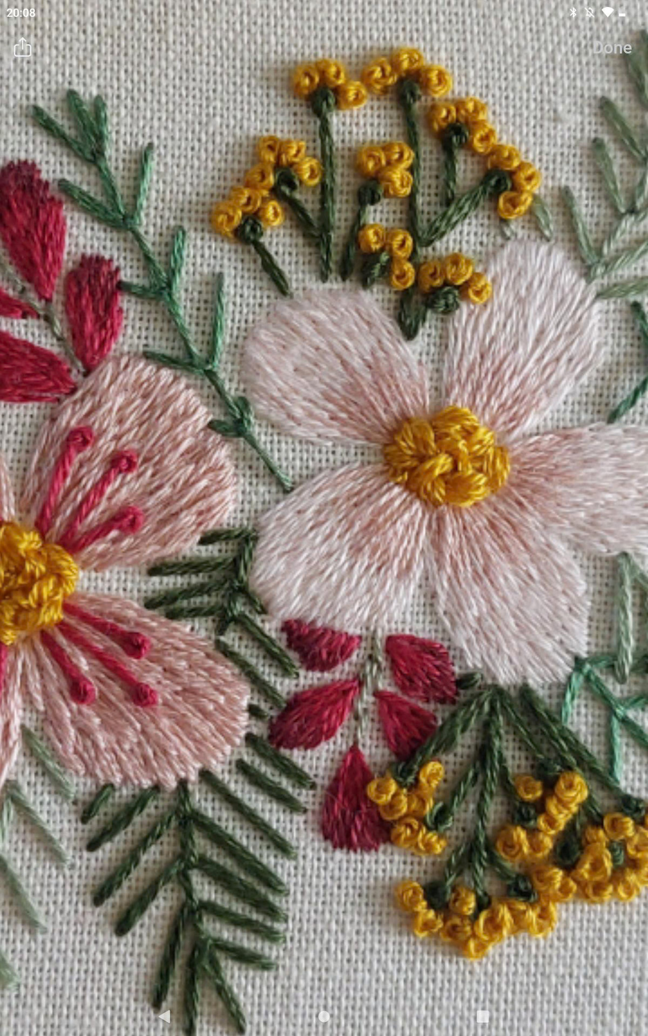 A close up of Angela's embroidery stitches on her hoop - filled with pink and yellow floral embroidery. The 'Fun Florals' pattern from inside the embroidery membership, Bloom Embroidery Academy