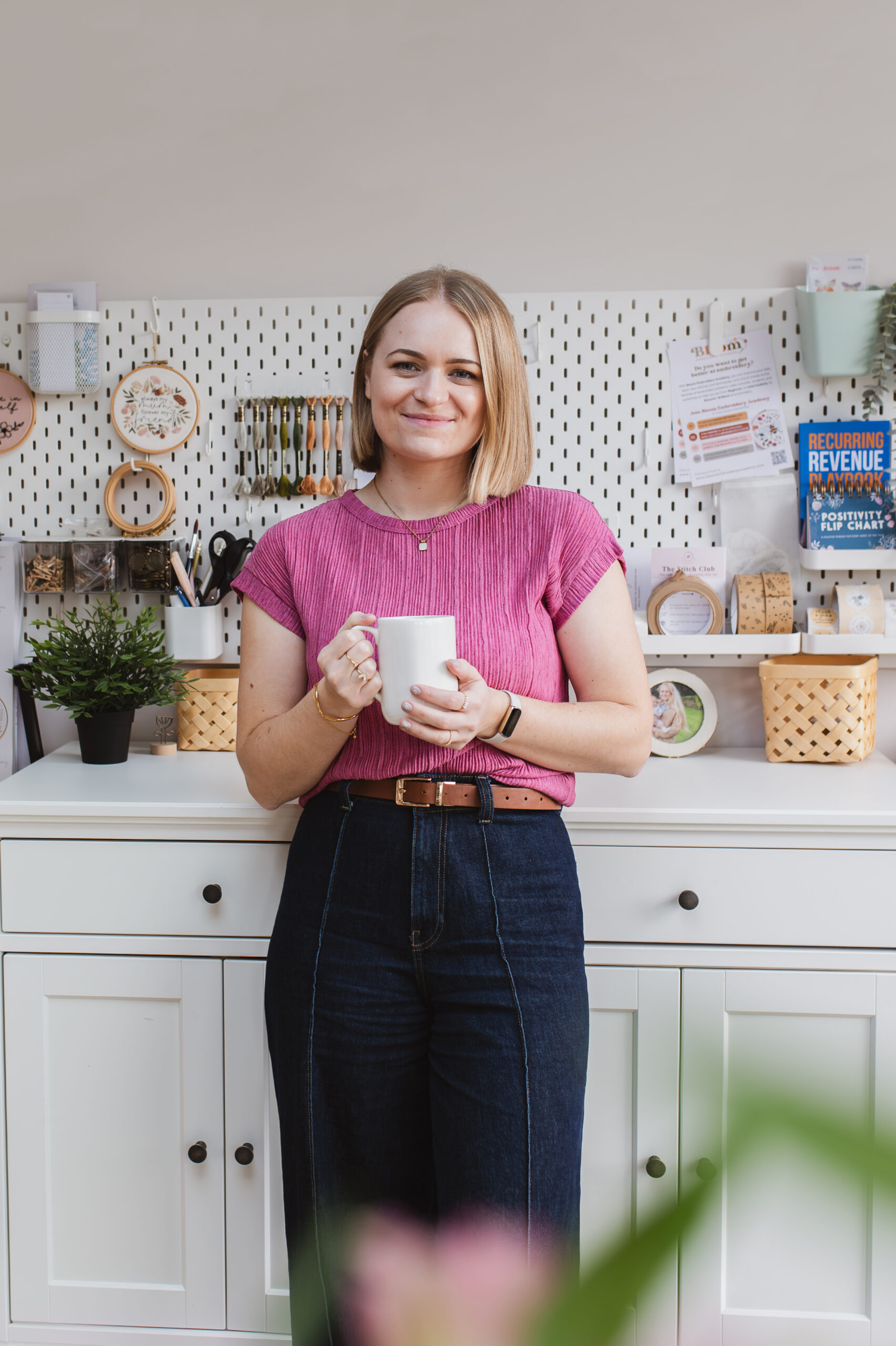 Sophie standing in her studio at Mindful Mantra Embroidery holding a cup of coffee
